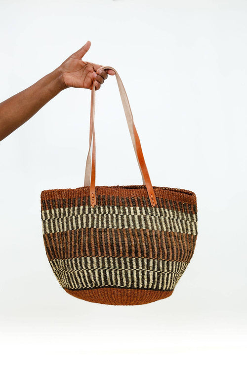 Woven basket with striped pattern held by a hand against a white background