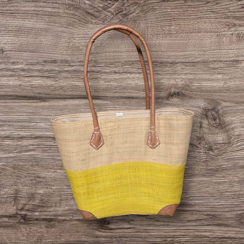 Tote bag with beige top half and yellow bottom half on a wooden surface