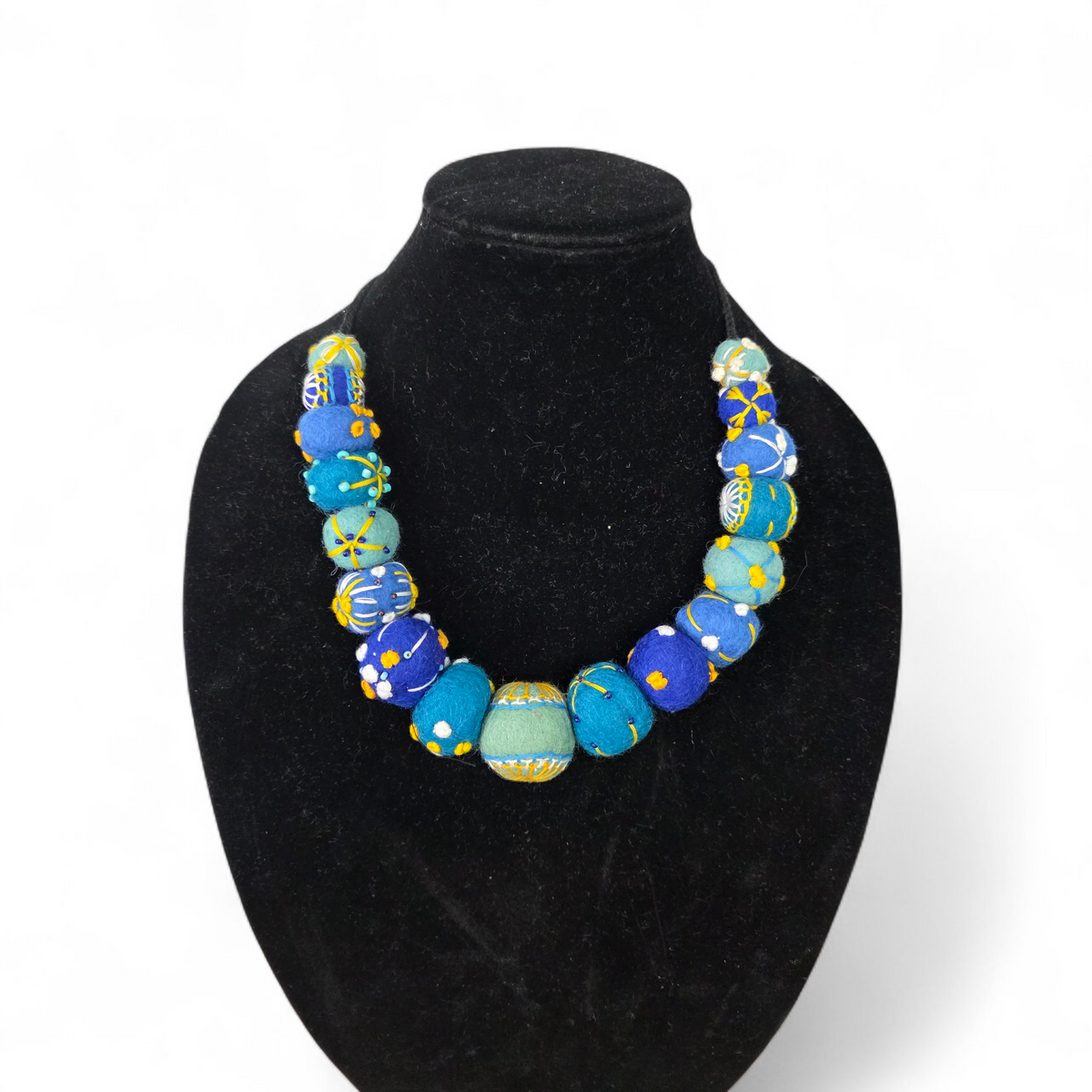 Necklace with blue and green beads on a black bust