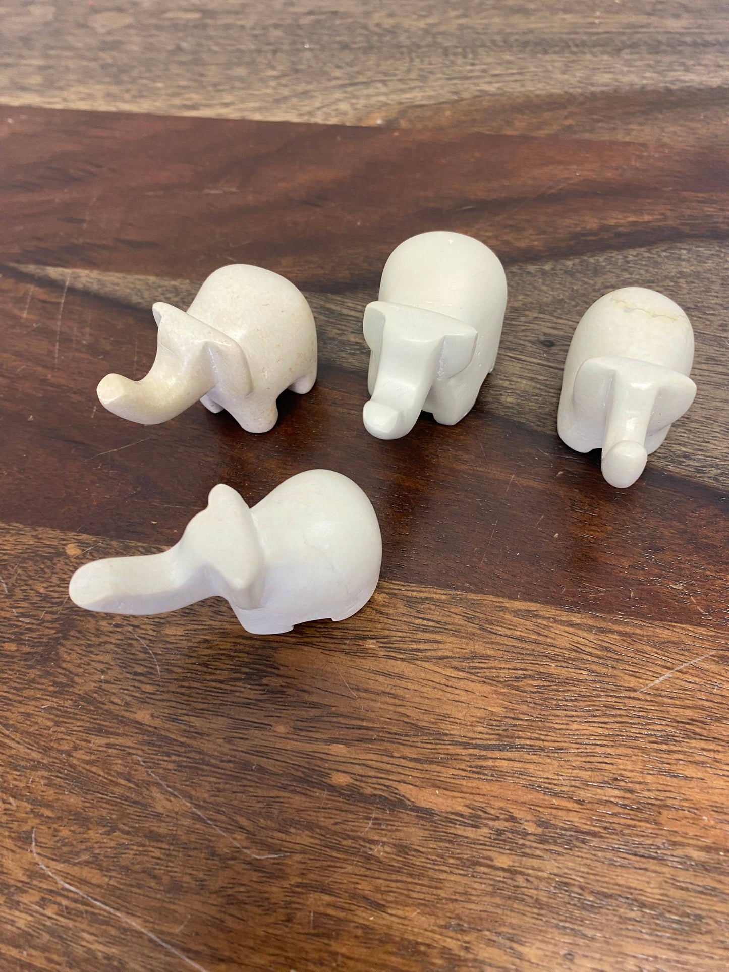 Four white elephant figurines on a wooden surface