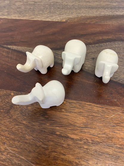 Four white elephant figurines on a wooden surface