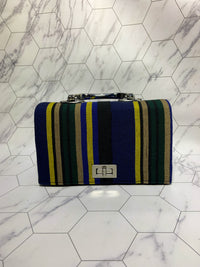 Striped handbag with blue, green, and yellow pattern on a marble floor.