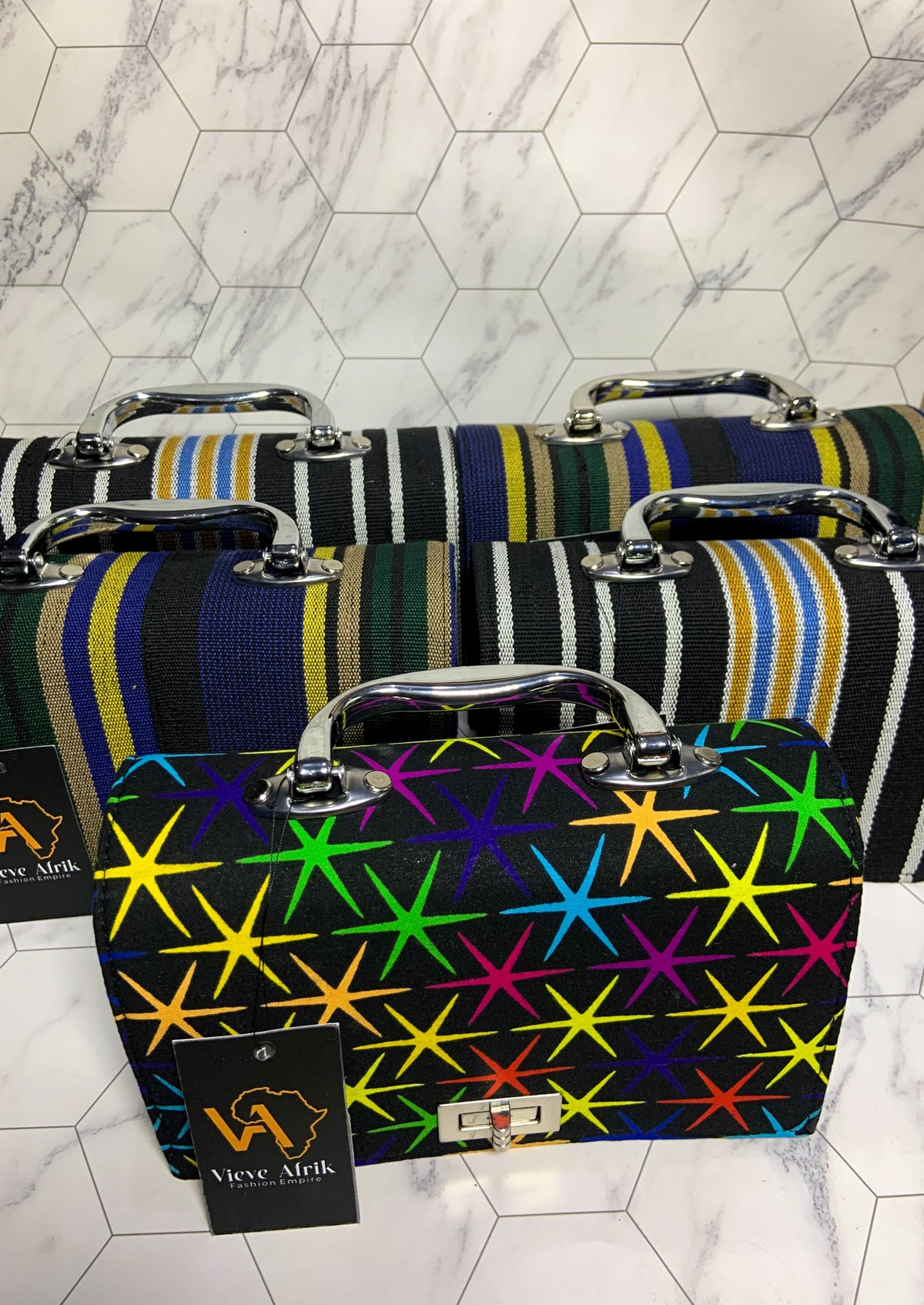 Colorful patterned briefcases on a marble floor with a visible brand tag.