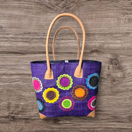 Purple tote bag with floral patterns on a wooden surface