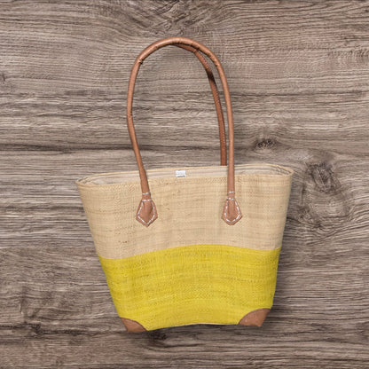 Tote bag with beige top half and yellow bottom half on a wooden surface